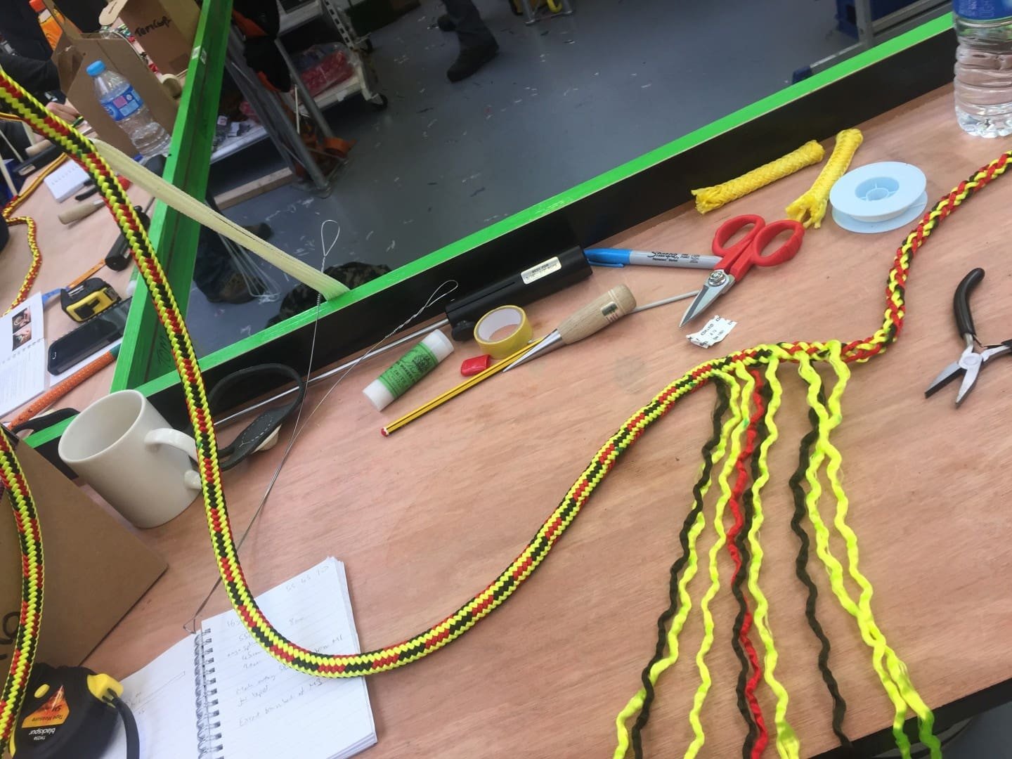 Braided cords and craft tools laid out on a workbench during rope-making