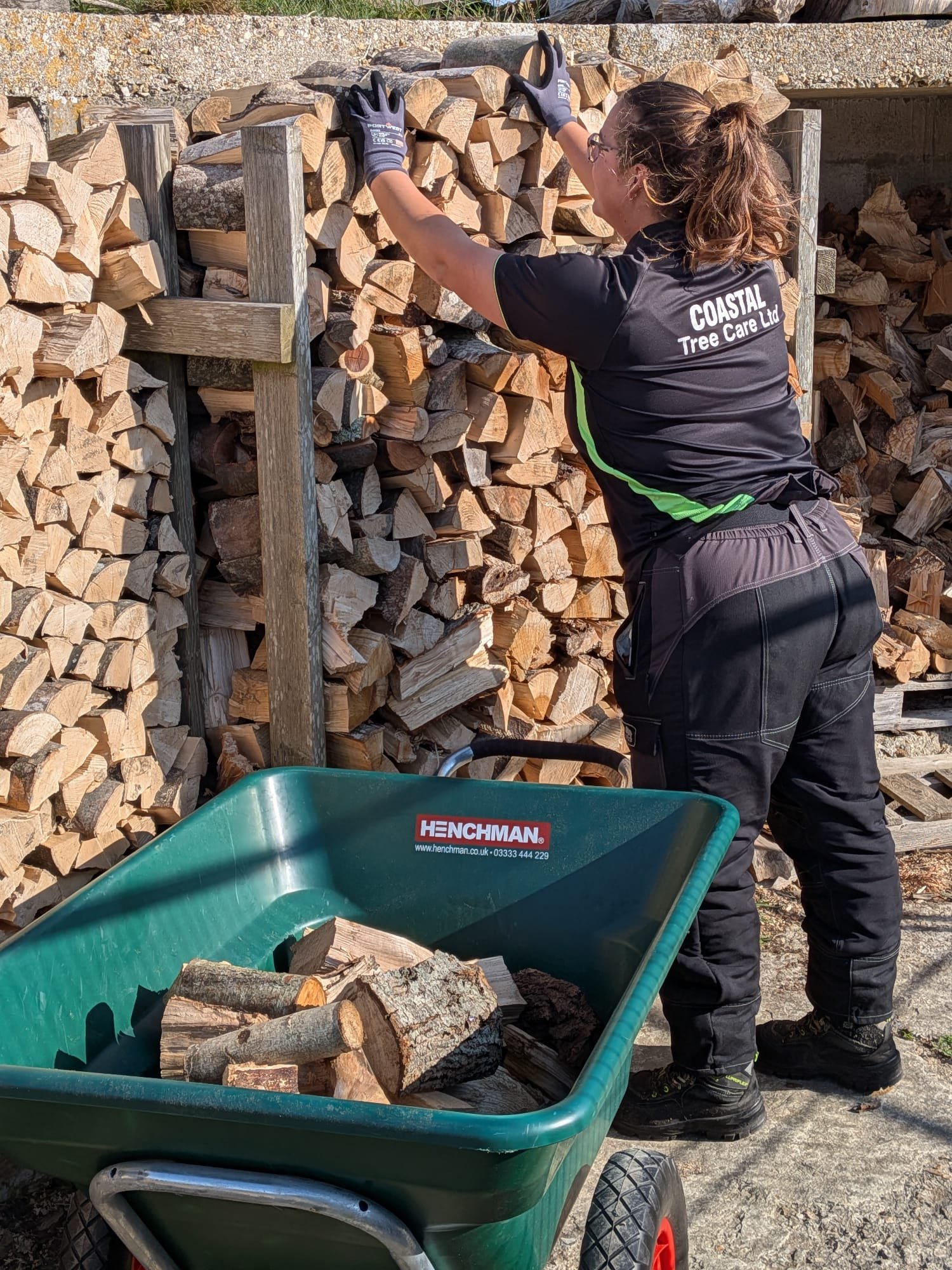 Firewood Storage at Coastal Tree Care Coastal Tree Care team member stacking split logs in a firewood store